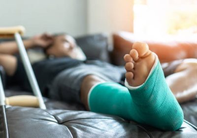 Bone fracture foot and leg on male patient with splint cast and crutches during surgery rehabilitation and orthopaedic recovery staying at home