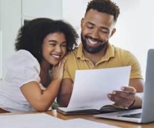 Couple celebrating financial freedom, using laptop, banking reports or statements to calculate budget, savings and finance. Happy debt free girlfriend and boyfriend with mortgage home loan approval